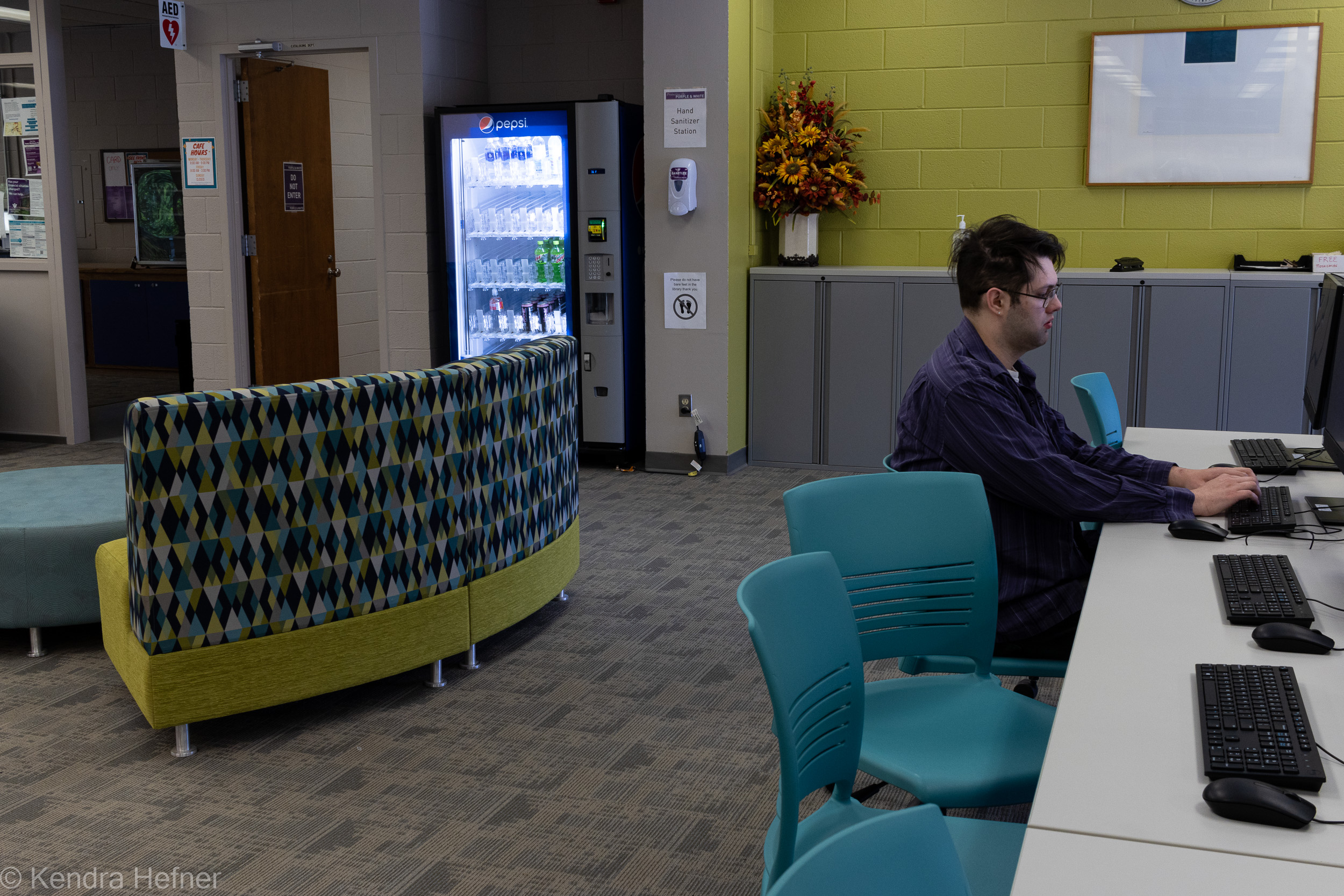 Elijah Westercamp, IW grad student and library graduate assistant sitting alone in a dimly lit library at the computer lab. Spring 2023.
